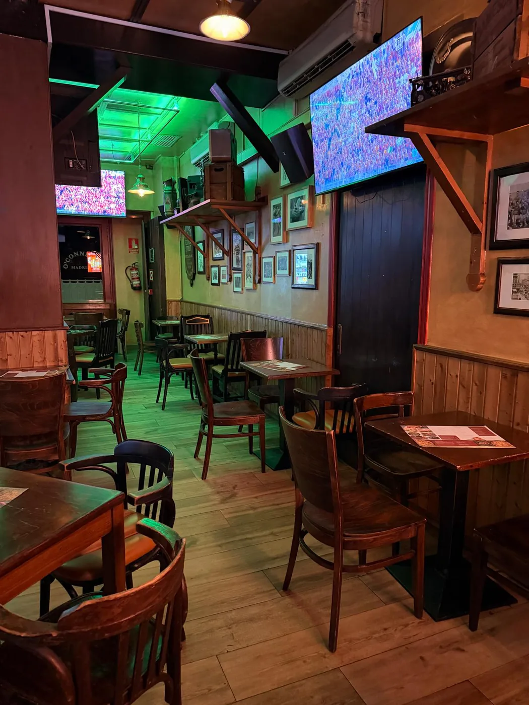 Tables and wall TVs in the seating area at O'Connell St near Sol